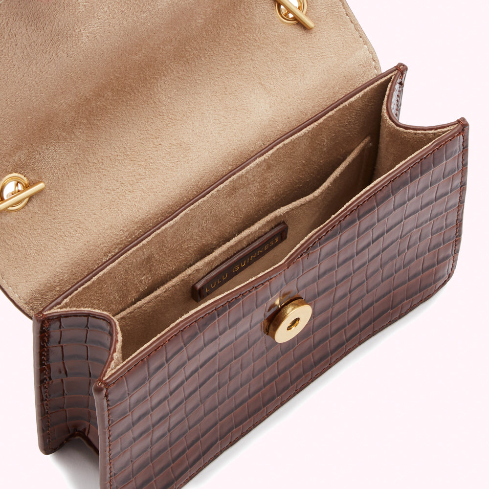 Brown Lulu Guinness crossbody bag open to show beige interior and gold hardware.