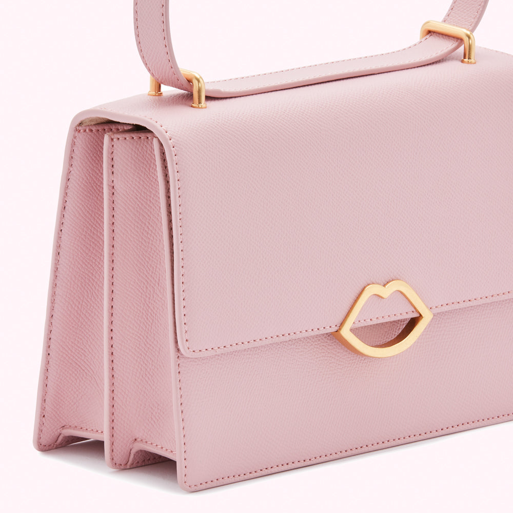 Close-up of a pale pink leather handbag with gold lip-shaped hardware.
