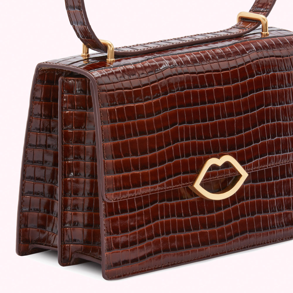 Brown crocodile-embossed leather handbag with gold lip-shaped clasp.
