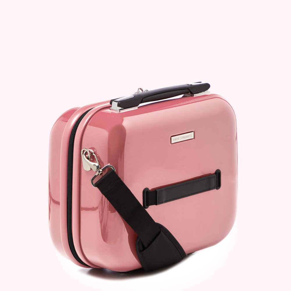 Pink hard-shell carry-on makeup case with black strap.
