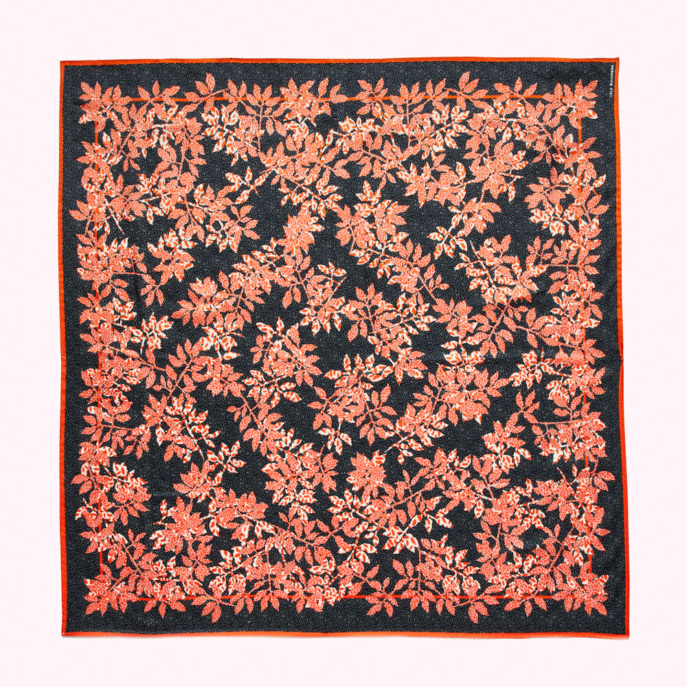 Square scarf with a repeating pattern of orange leaves on a black background.