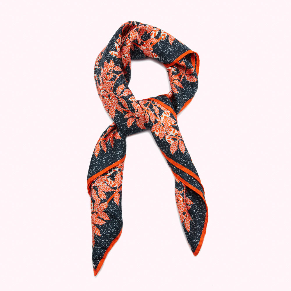 Dark blue scarf with orange leaf pattern, knotted.