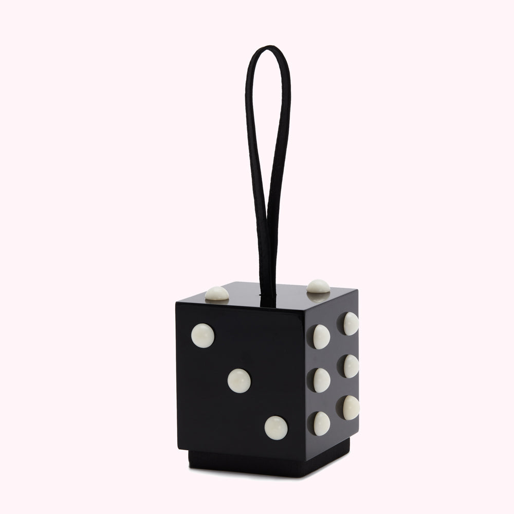 Black cube-shaped bag with off-white dots and a black leather loop.
