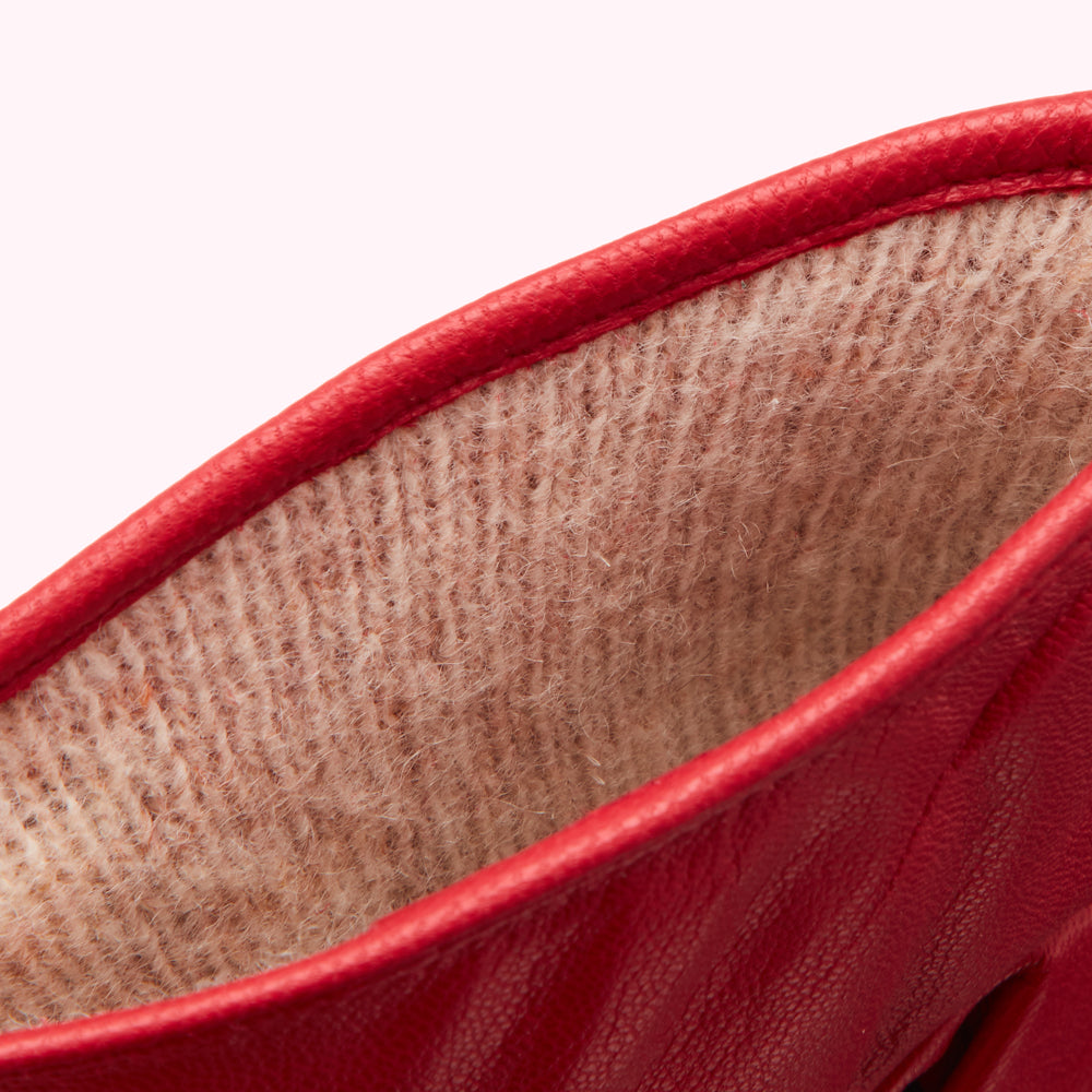Close-up of the inside of a red leather glove, showing the beige lining.
