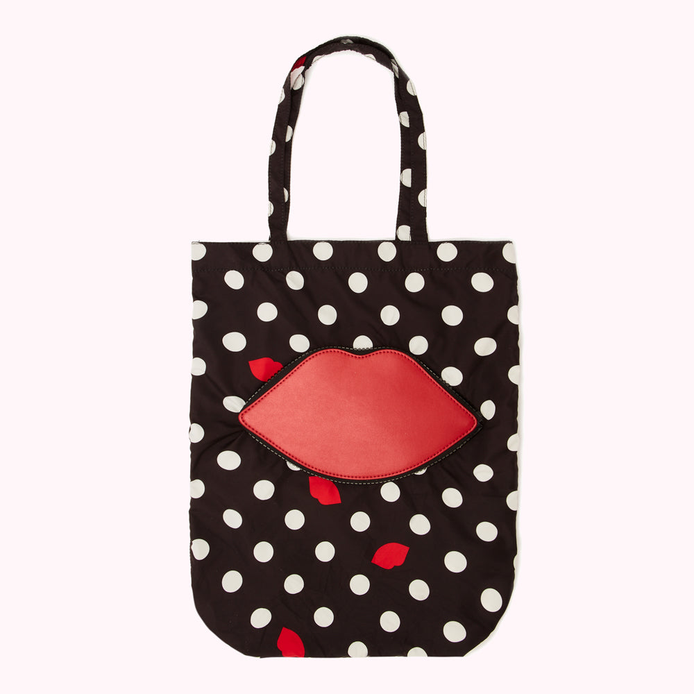 Black and white polka dot tote bag with a large red lip appliqué©.