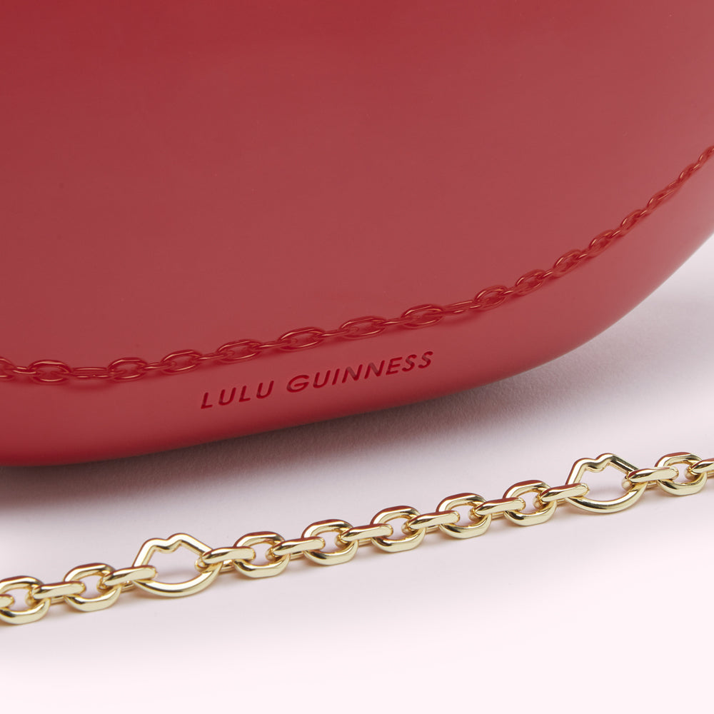 Close-up of a red Lulu Guinness handbag with a gold chain strap.