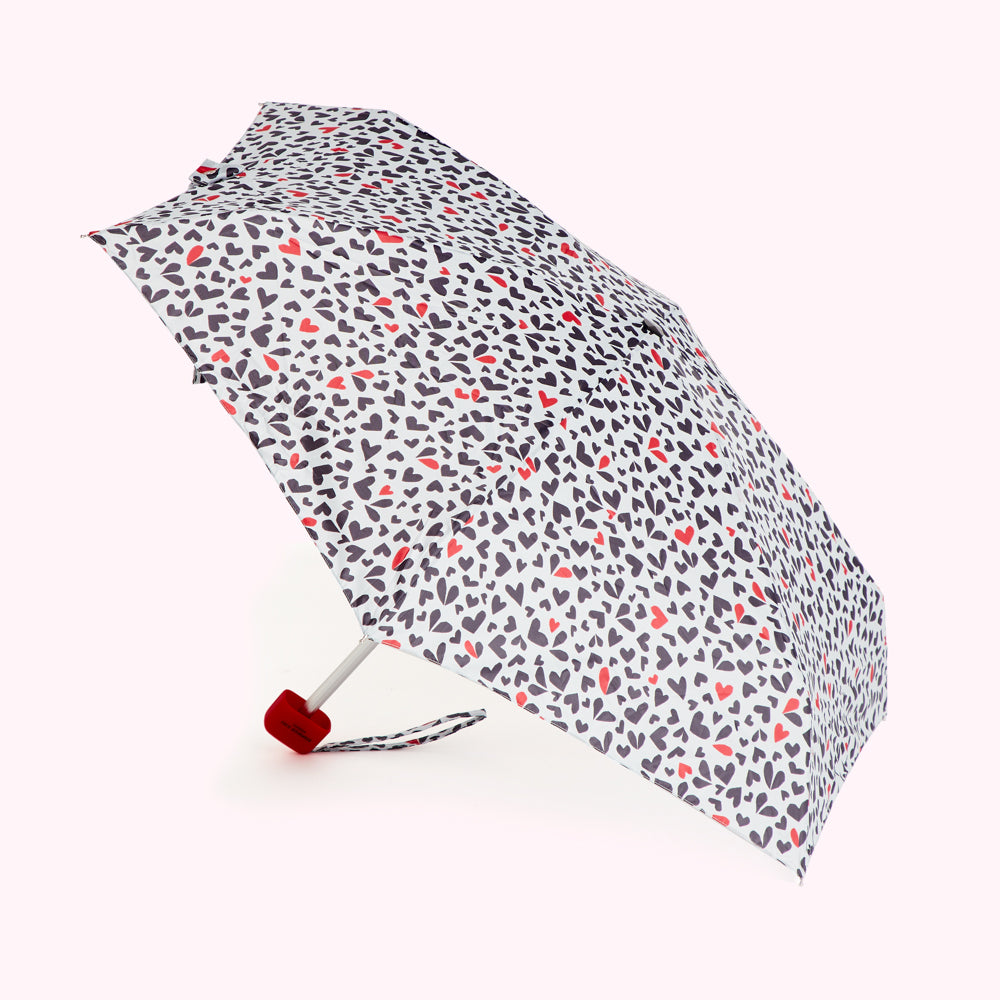 Compact umbrella with a pattern of dark gray and red hearts on a white background.