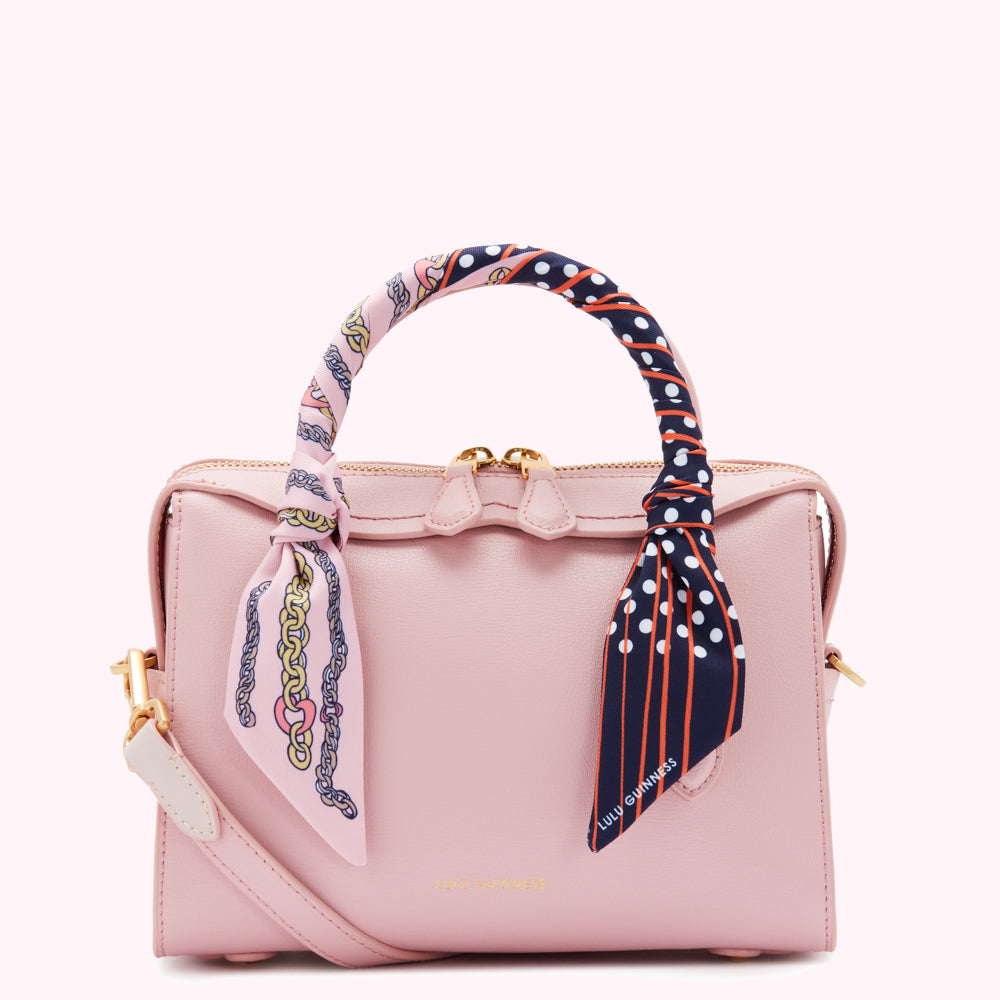 Pink Lulu Guinness handbag with a patterned scarf handle.

