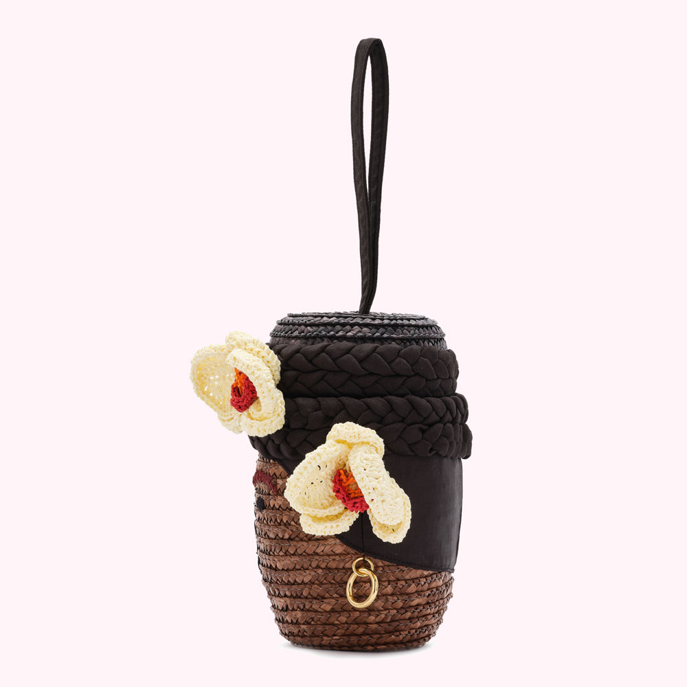 Brown and beige woven raffia handbag shaped like a woman's face, with crocheted flowers.