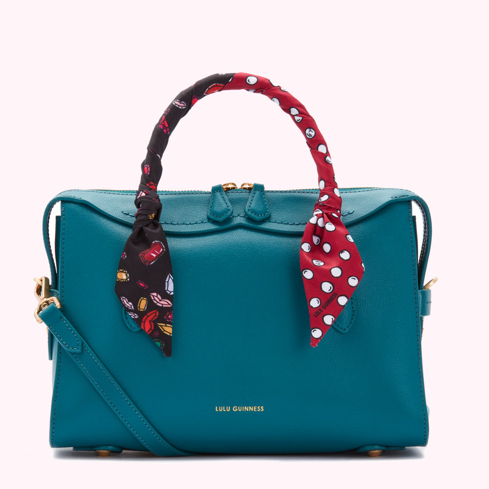 Teal Lulu Guinness satchel with a red and black patterned scarf tied to the handles.