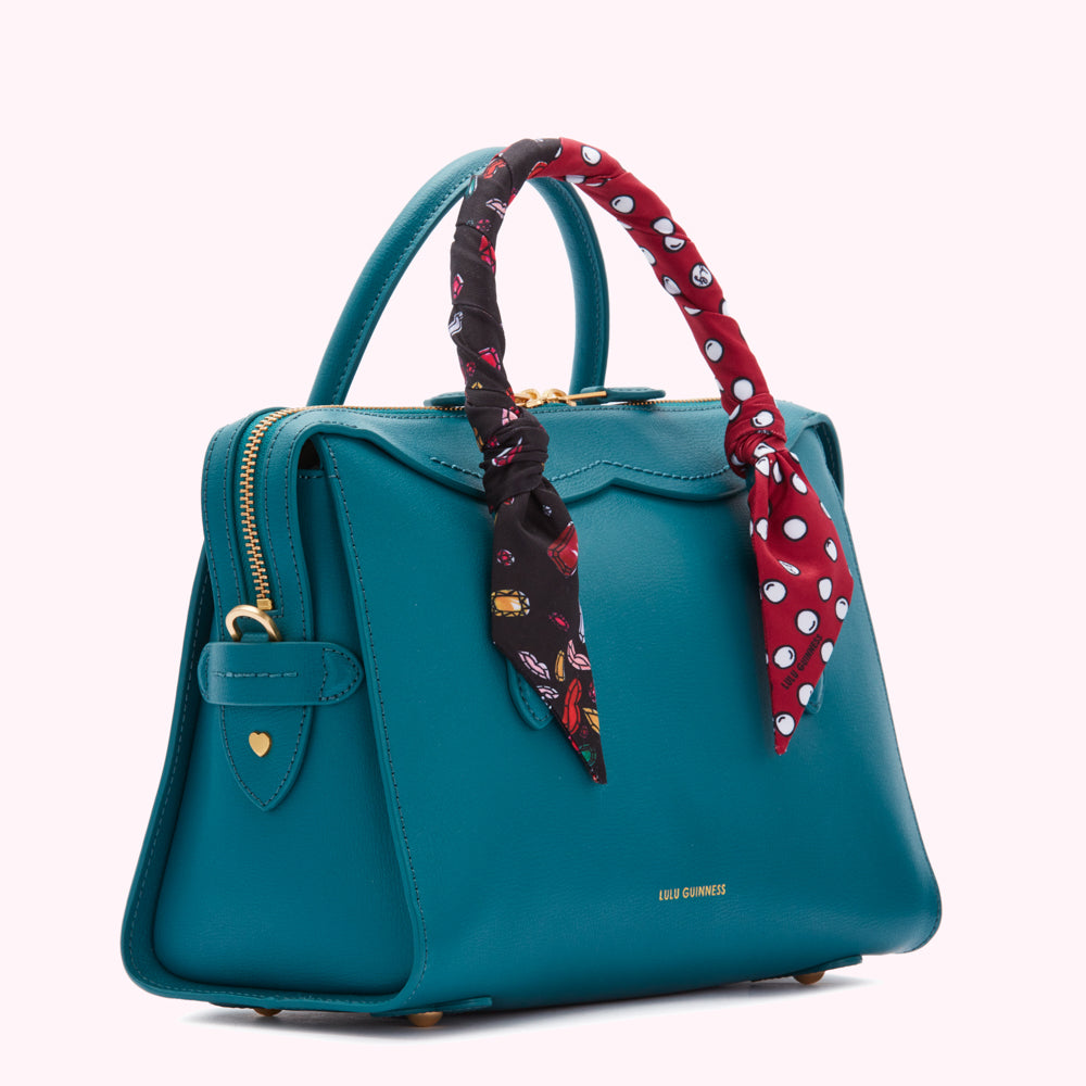 Teal Lulu Guinness satchel with a red and black patterned scarf tied to the handles.