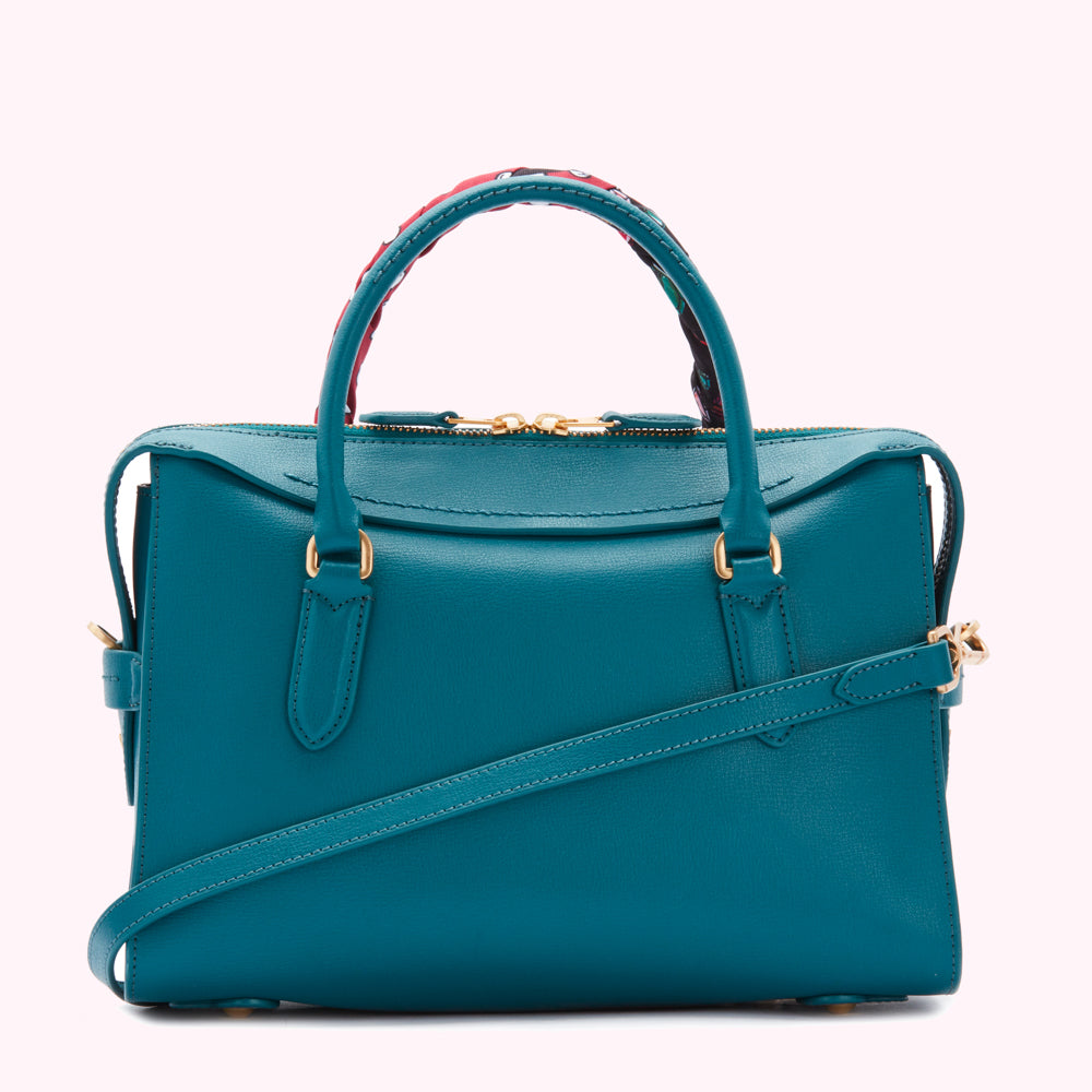 Teal leather handbag with gold hardware and patterned top handles.
