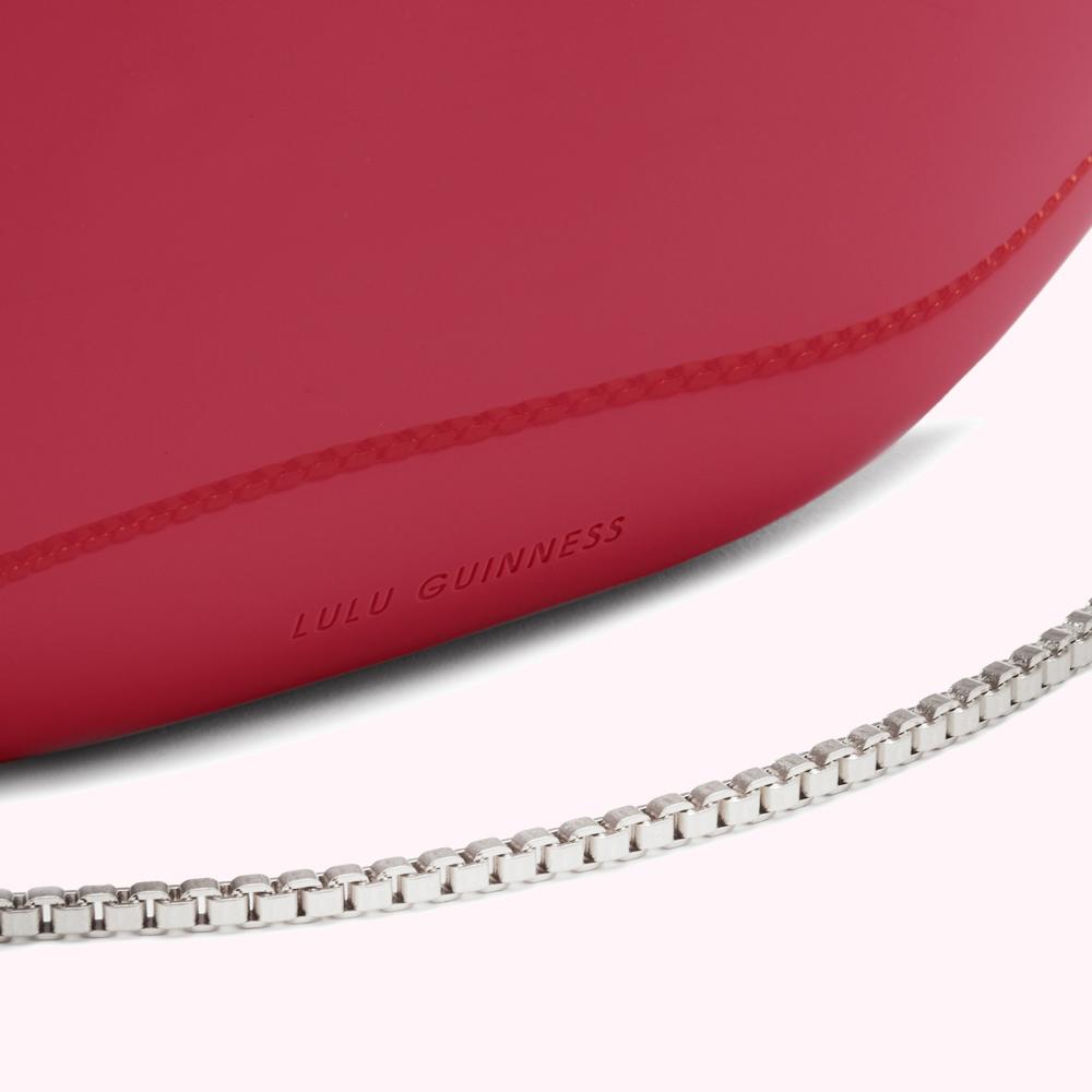 Close-up of a pink Lulu Guinness bag with a silver chain strap.
