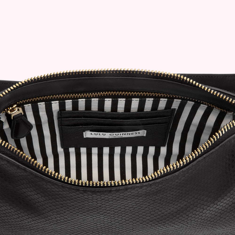 Open black Lulu Guinness clutch with gold zipper and black and white striped interior.
