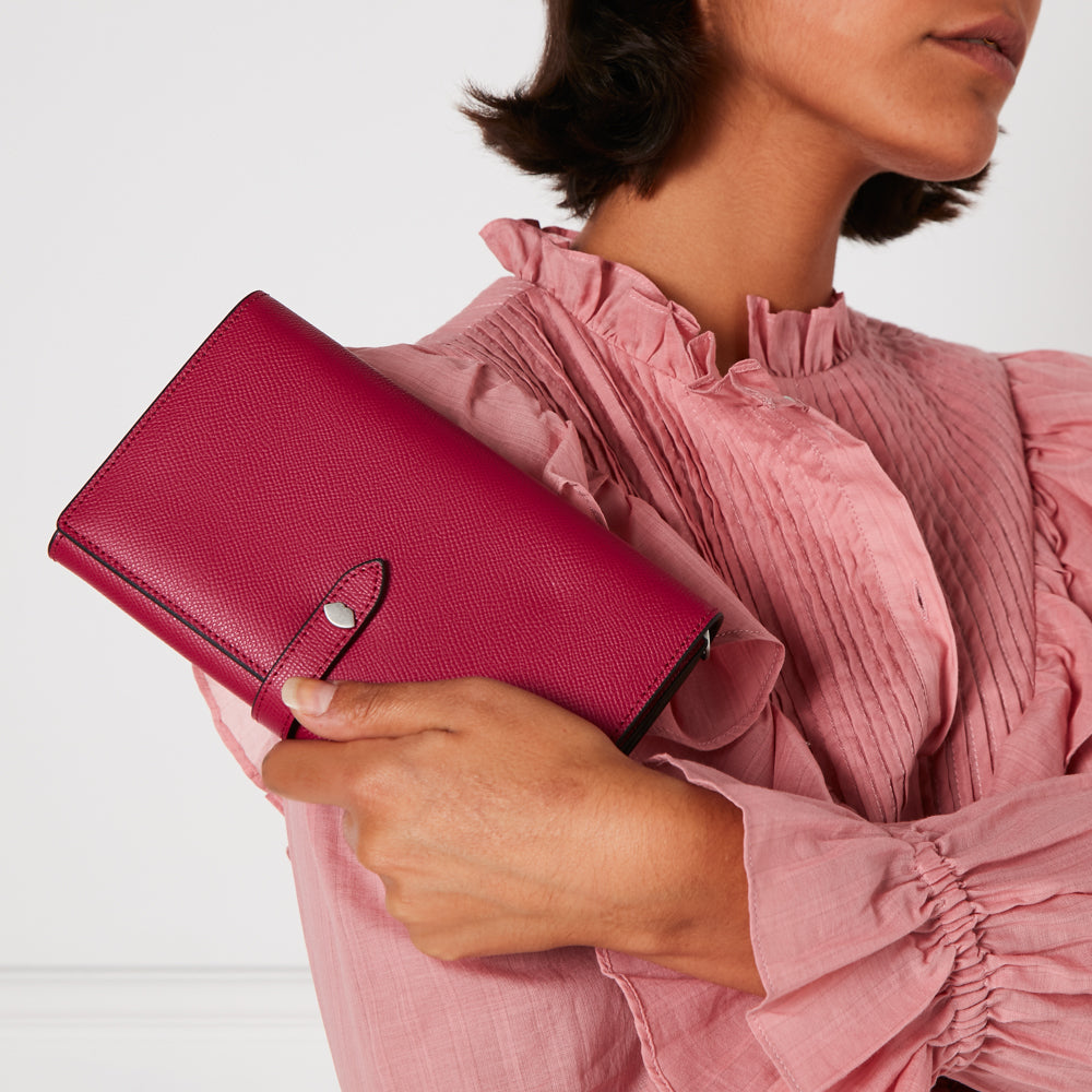 Woman holding a crimson leather wallet.