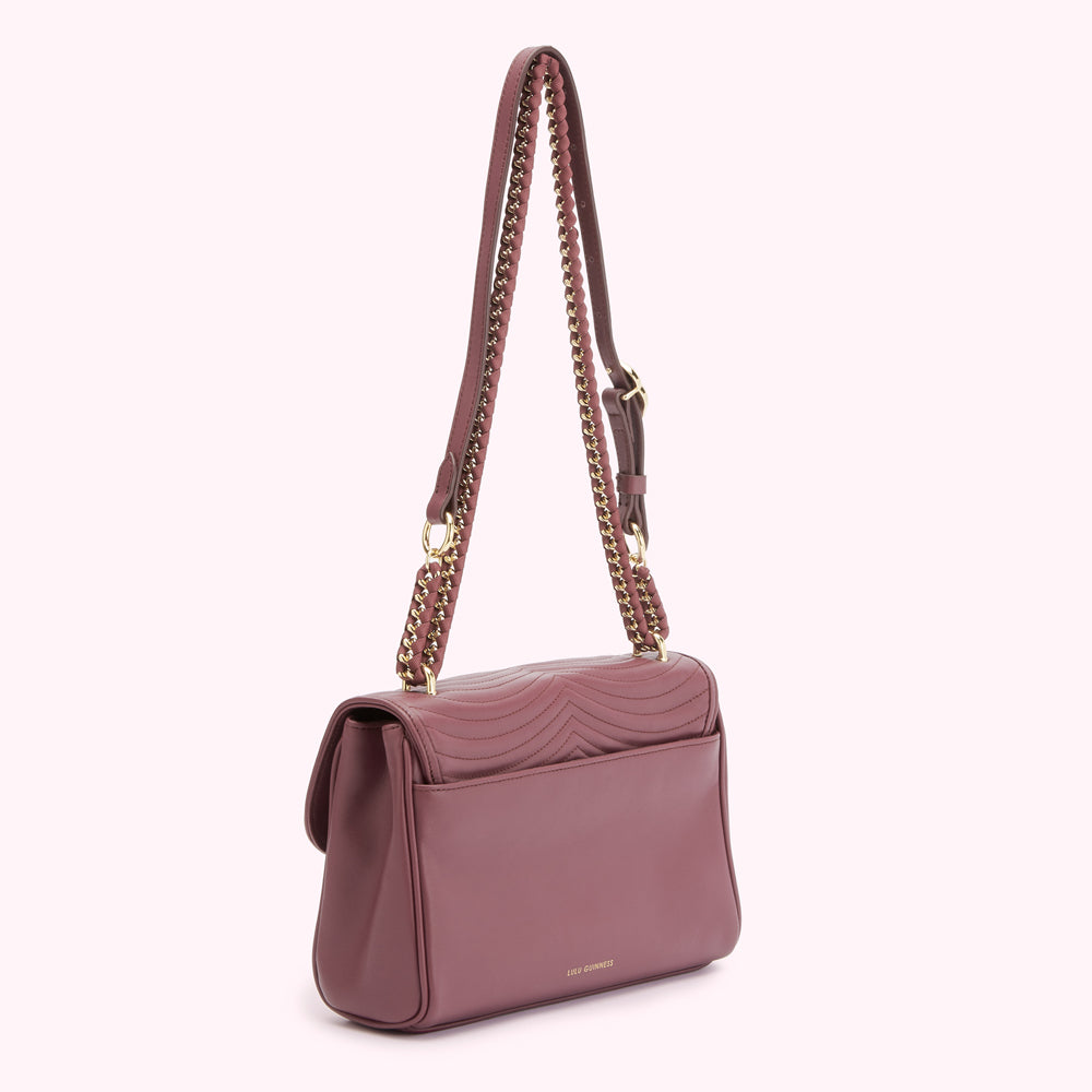 A mauve quilted crossbody bag with a gold chain strap.