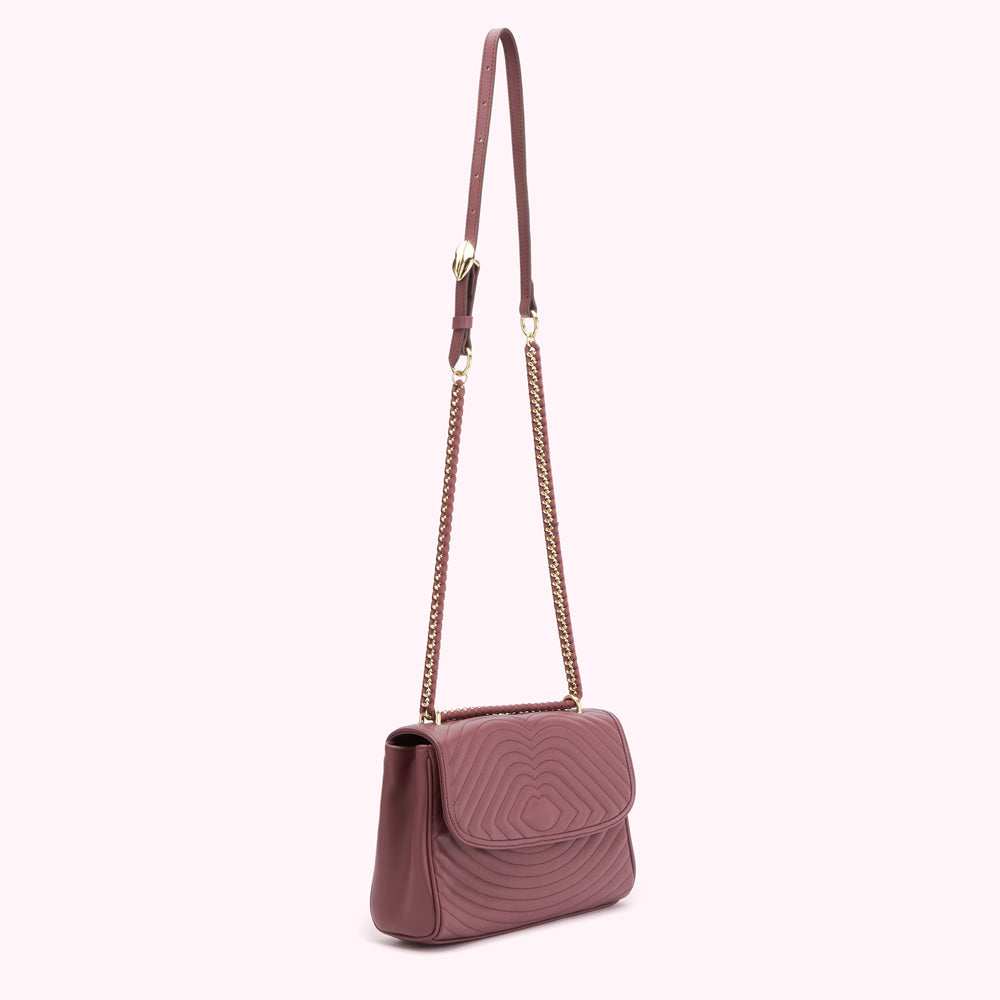 A mauve quilted crossbody bag with a gold chain strap.