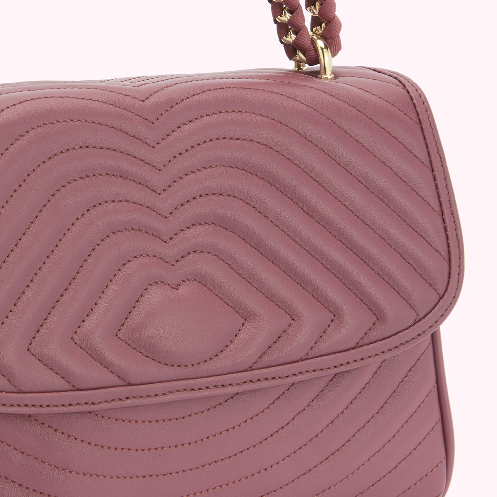 Close-up of a mauve quilted leather handbag with a gold chain strap.

