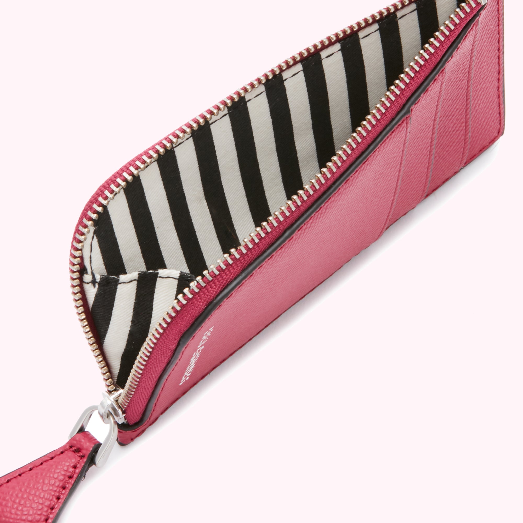 Close-up of a pink cardholder with a black and white striped interior lining and silver zipper.