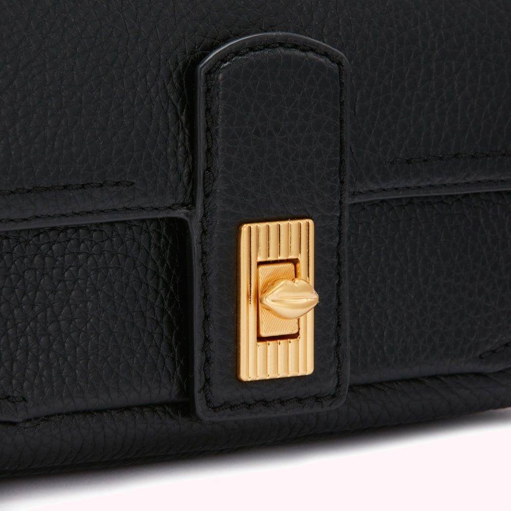 Close-up of a black leather handbag's clasp, featuring gold-toned hardware in the shape of lips.
