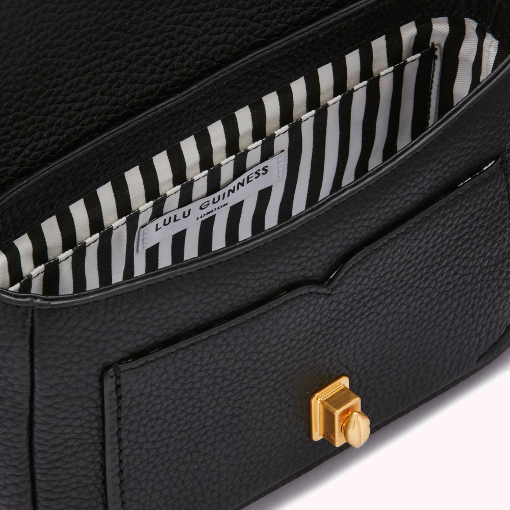 Close-up view of the inside of a black Lulu Guinness handbag, showcasing the brand label and the black and white striped lining.