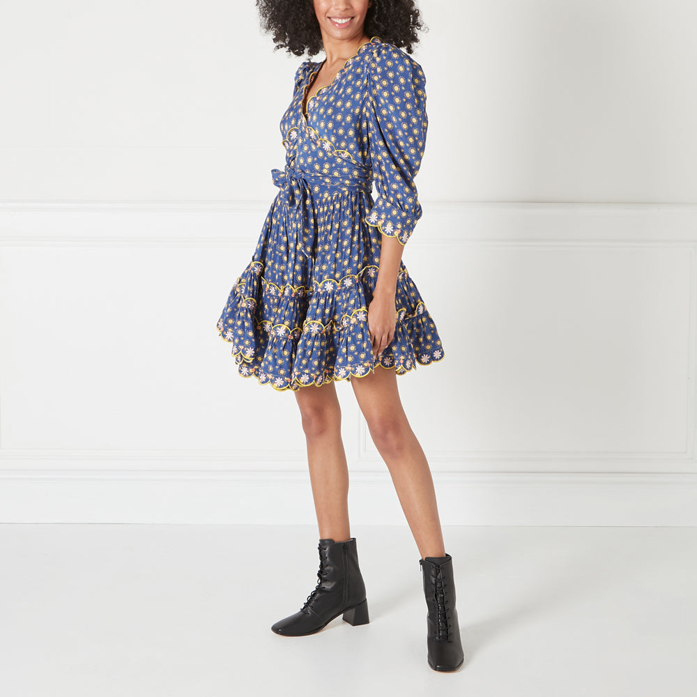 Woman wearing a blue floral mini dress and black lace-up boots against a white background.
