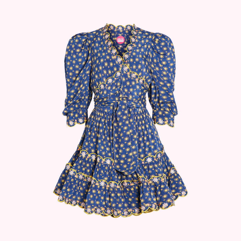Blue mini wrap dress with yellow sun and daisy print, puff sleeves, and scalloped edges.
