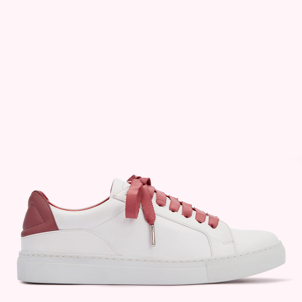 White leather sneaker with dusty rose heel and laces against a white background.