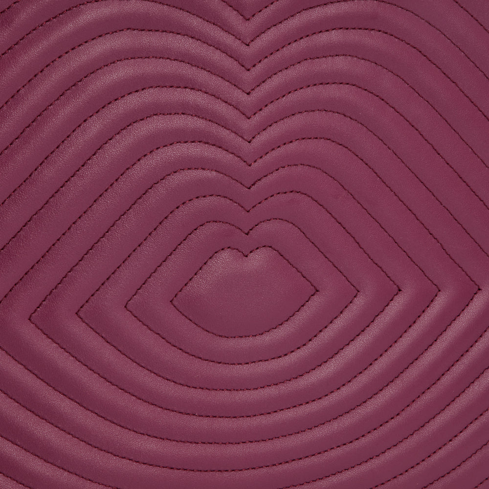 Close-up of quilted burgundy leather with a repeating heart-shaped pattern.
