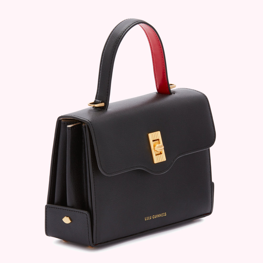 Black Lulu Guinness handbag with red interior detail and gold clasp.