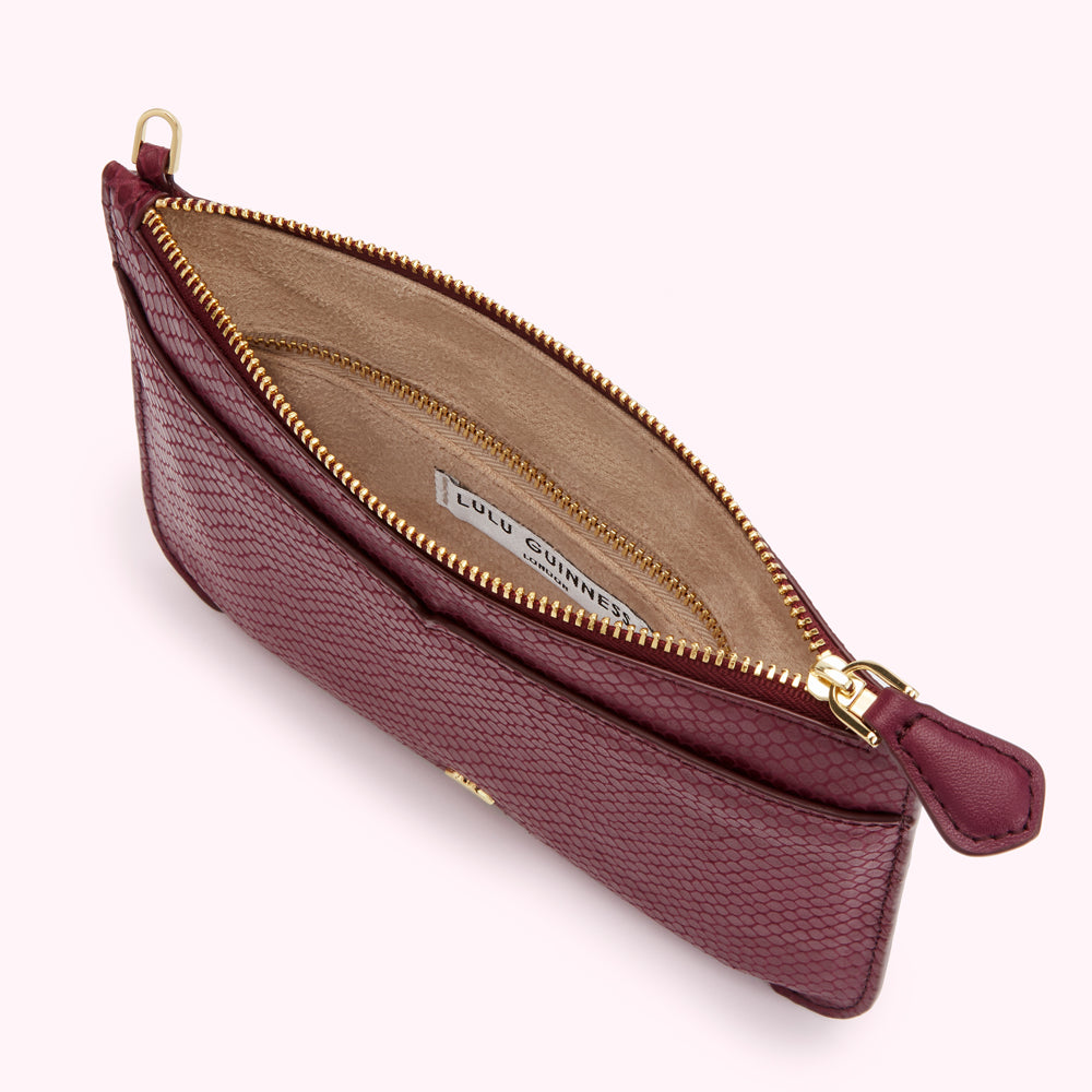 Open burgundy Lulu Guinness zip-around pouch with beige interior and gold zipper.
