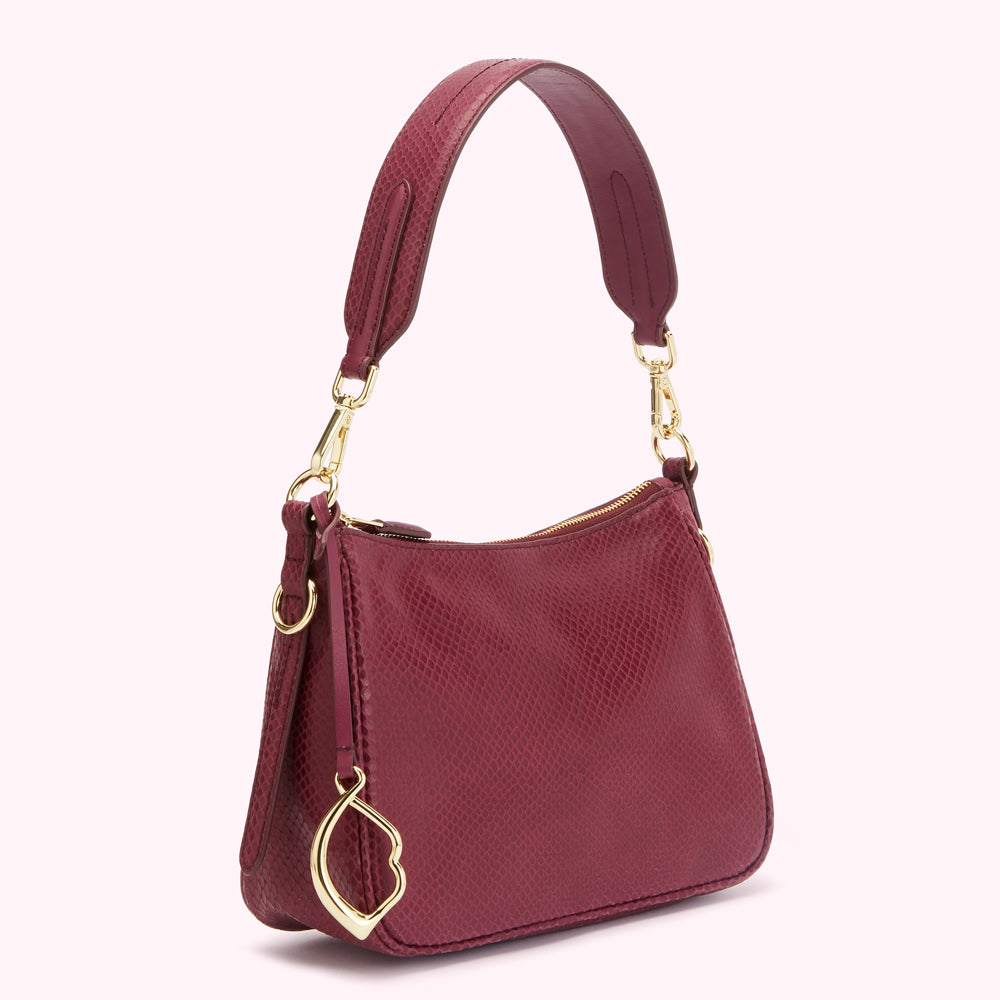 Burgundy snakeskin-textured handbag with gold-toned hardware and a small heart-shaped charm.
