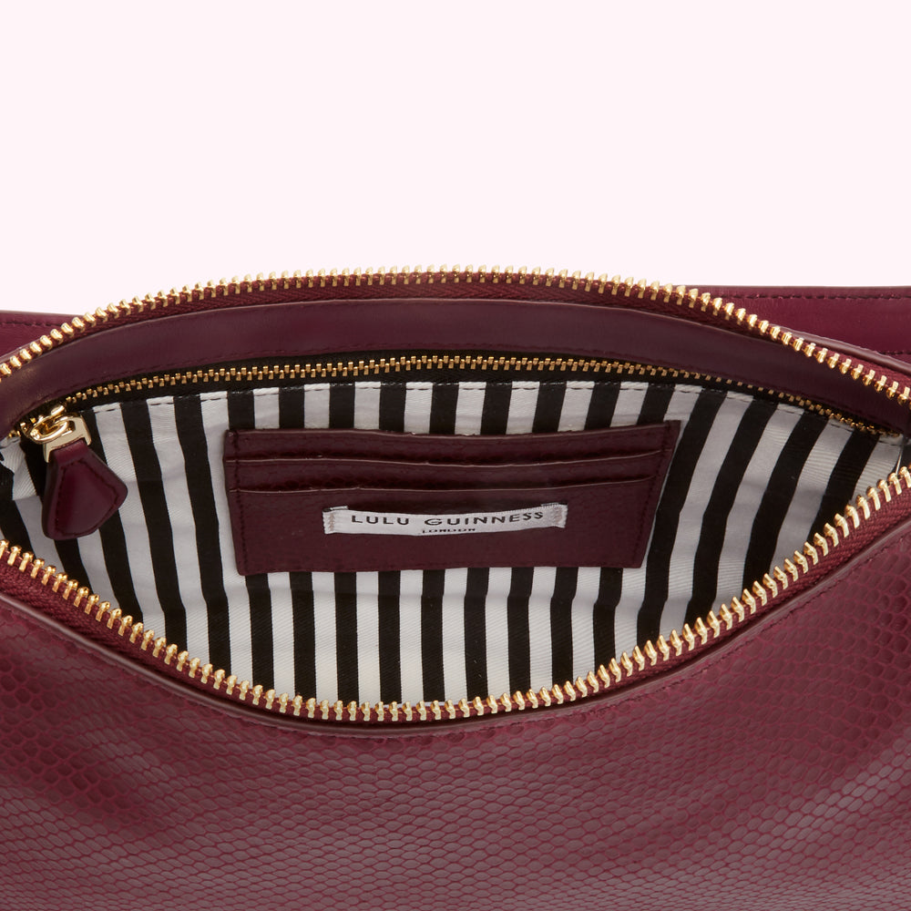 Open burgundy Lulu Guinness purse with black and white striped interior.
