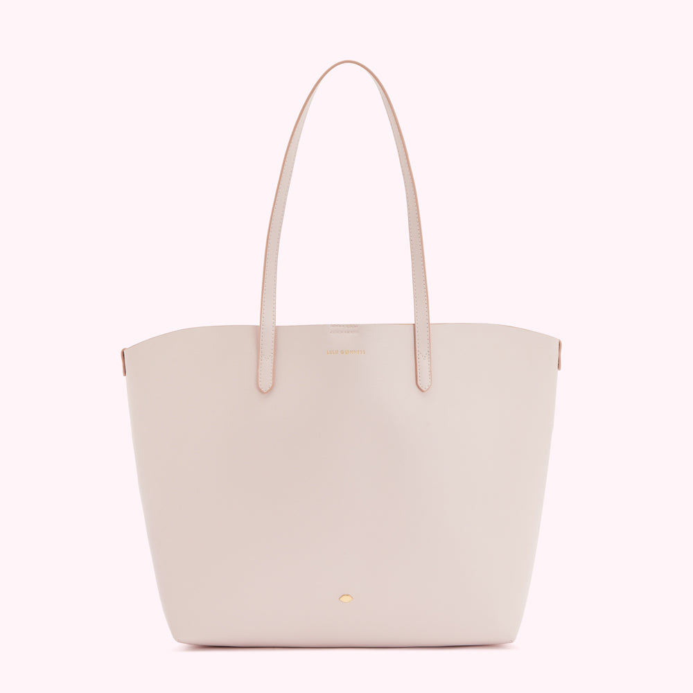 A light pink leather tote bag with light pink leather straps and a small gold logo.