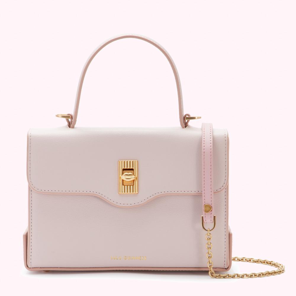 A pale pink leather handbag with gold hardware and a detachable chain strap against a white background.