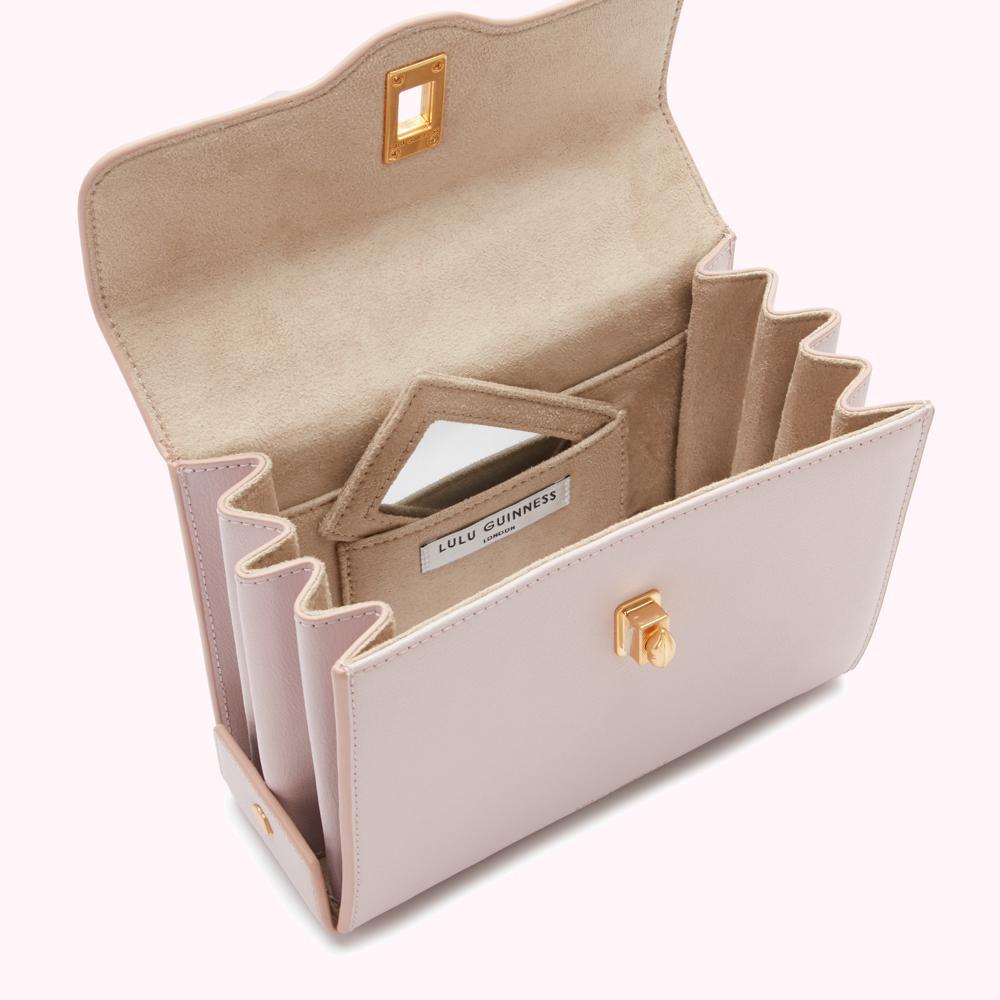 Open blush pink Lulu Guinness handbag showing beige interior and gold clasp.

