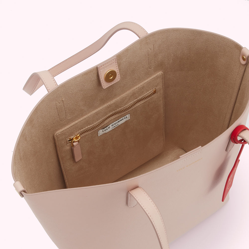 Interior view of a blush pink Lulu Guinness tote bag with a beige lining and an interior zip pocket.