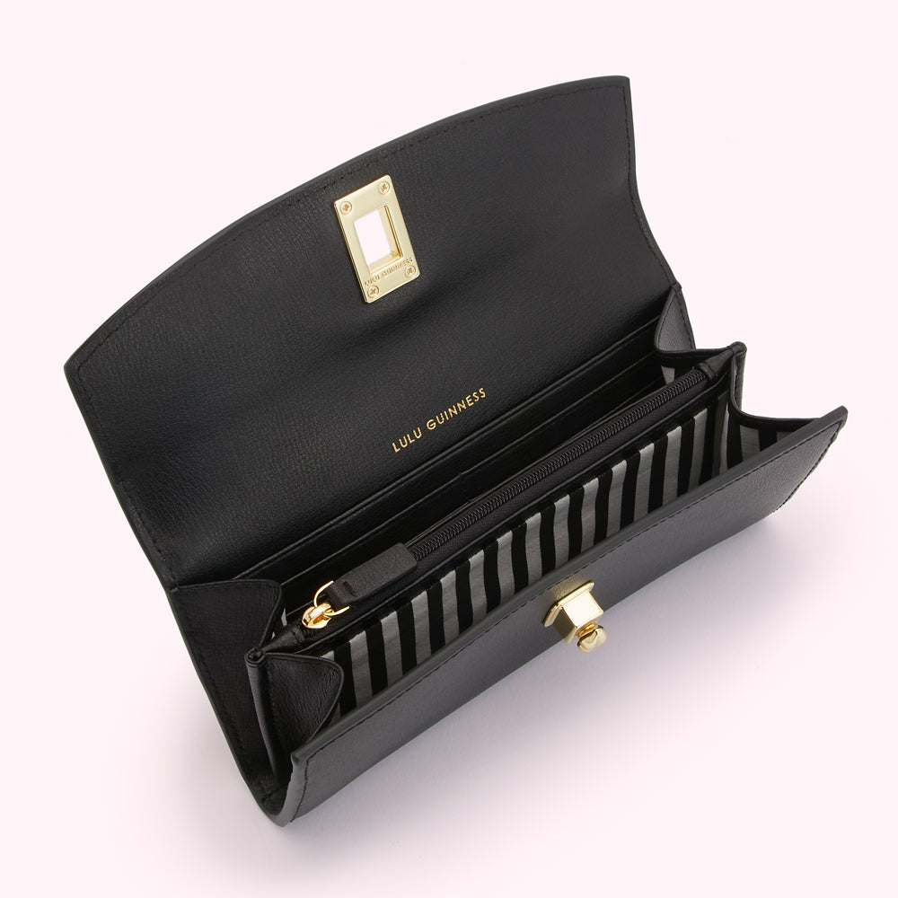 Open black Lulu Guinness wallet with gold accents and striped interior.
