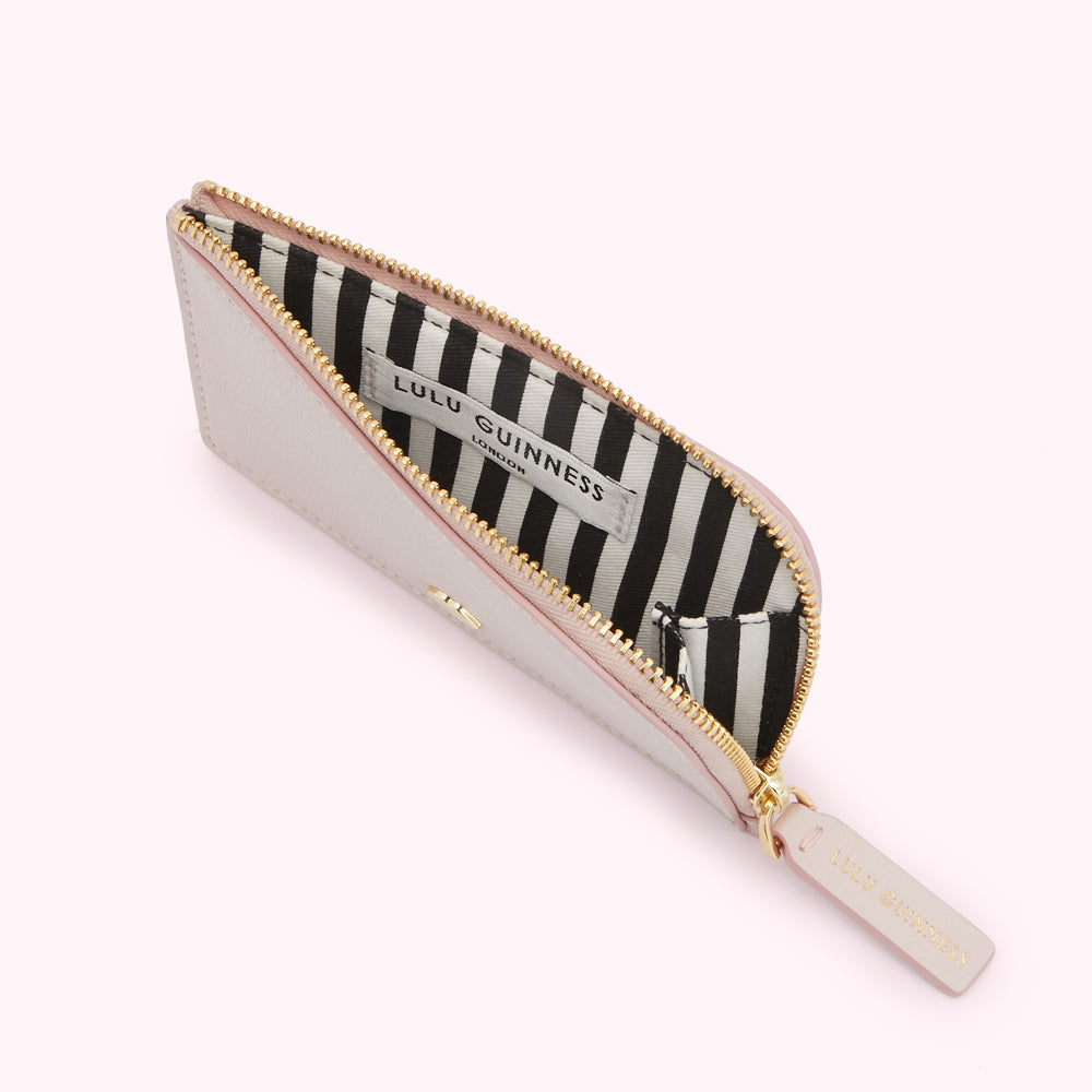 Open blush pink Lulu Guinness zip-around cardholder with black and white striped interior.
