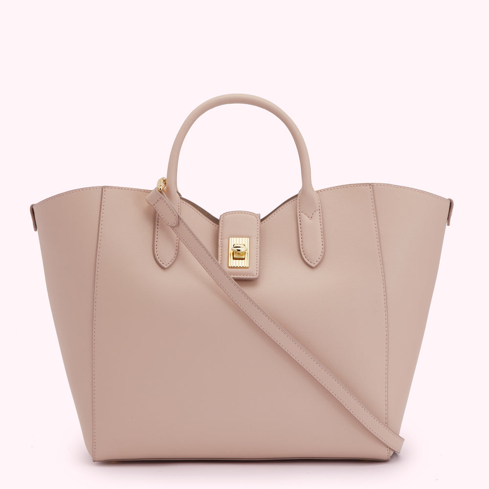 A blush-pink leather tote bag with a gold clasp and a long shoulder strap.
