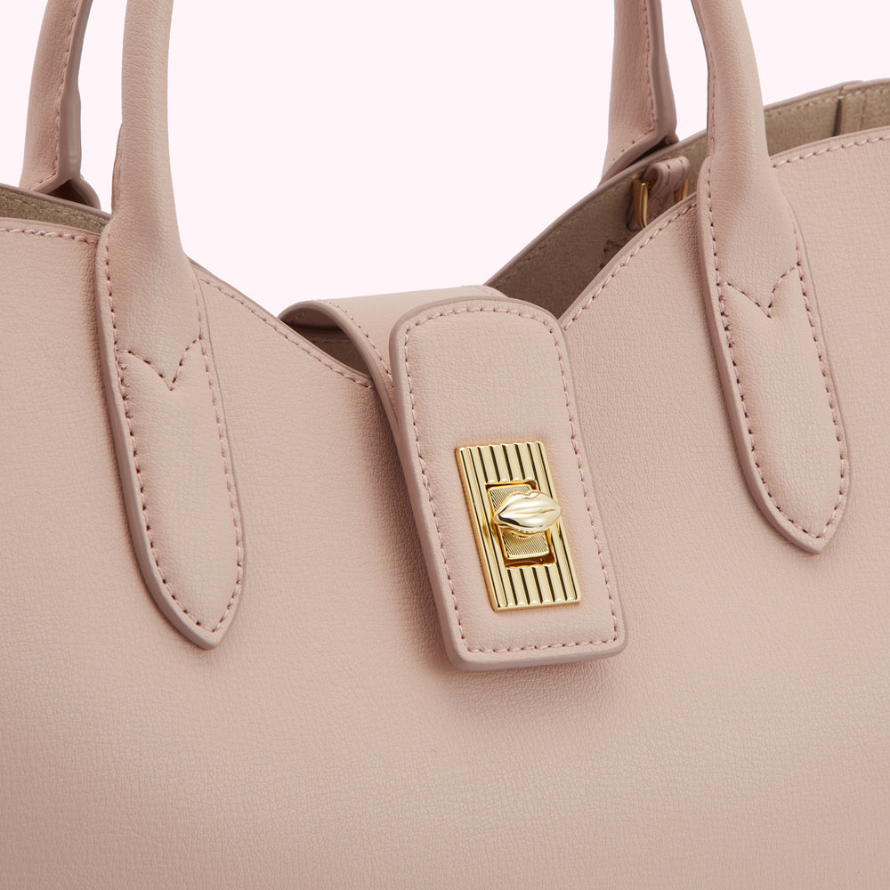 Close-up of a blush-pink leather handbag with a gold clasp.
