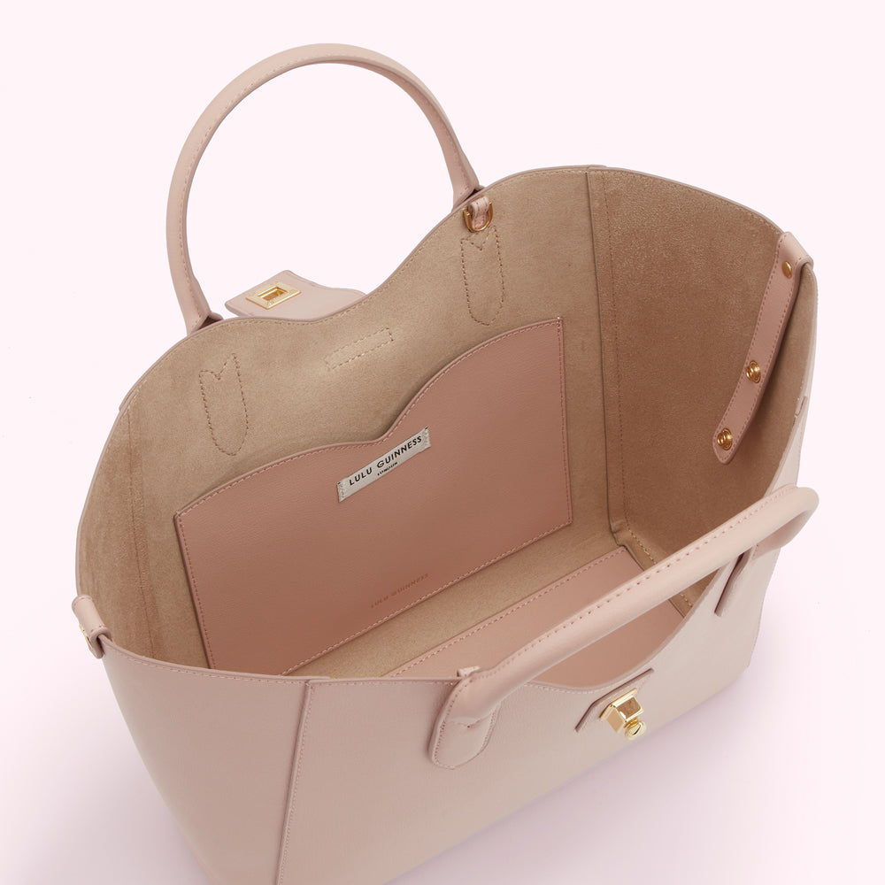 A pale pink Lulu Guinness tote bag viewed from above, showcasing its interior with a suede lining and smaller interior pocket.