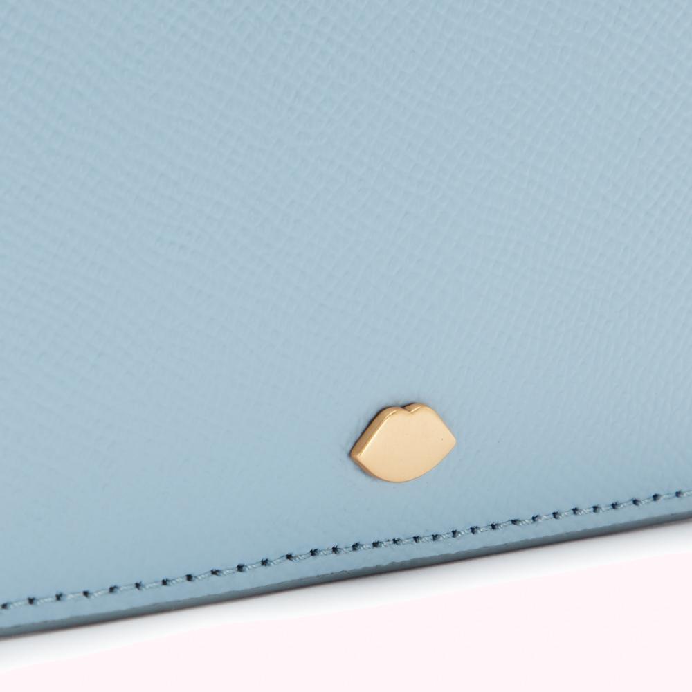 Close-up of a light blue leather wallet with a gold lip-shaped logo.
