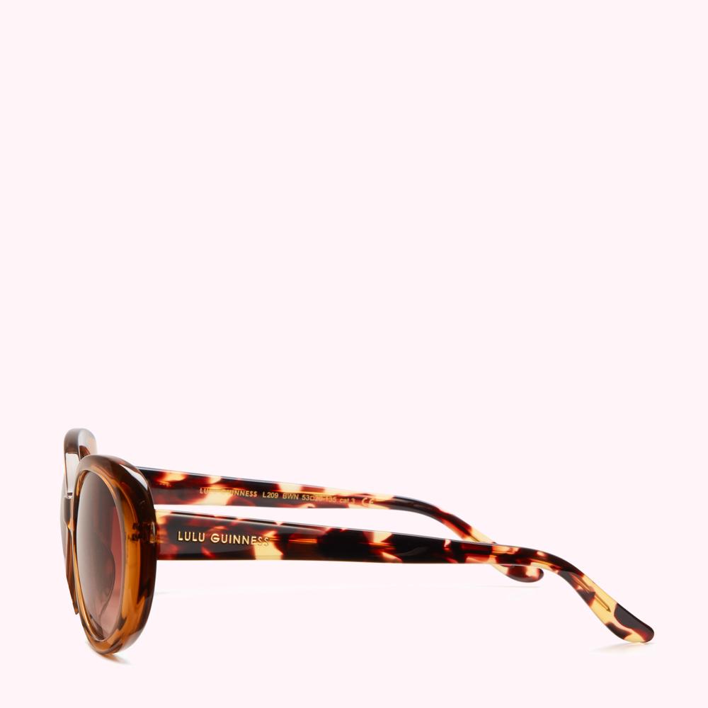 Tortoiseshell Lulu Guinness sunglasses with brown lenses on a white background.
