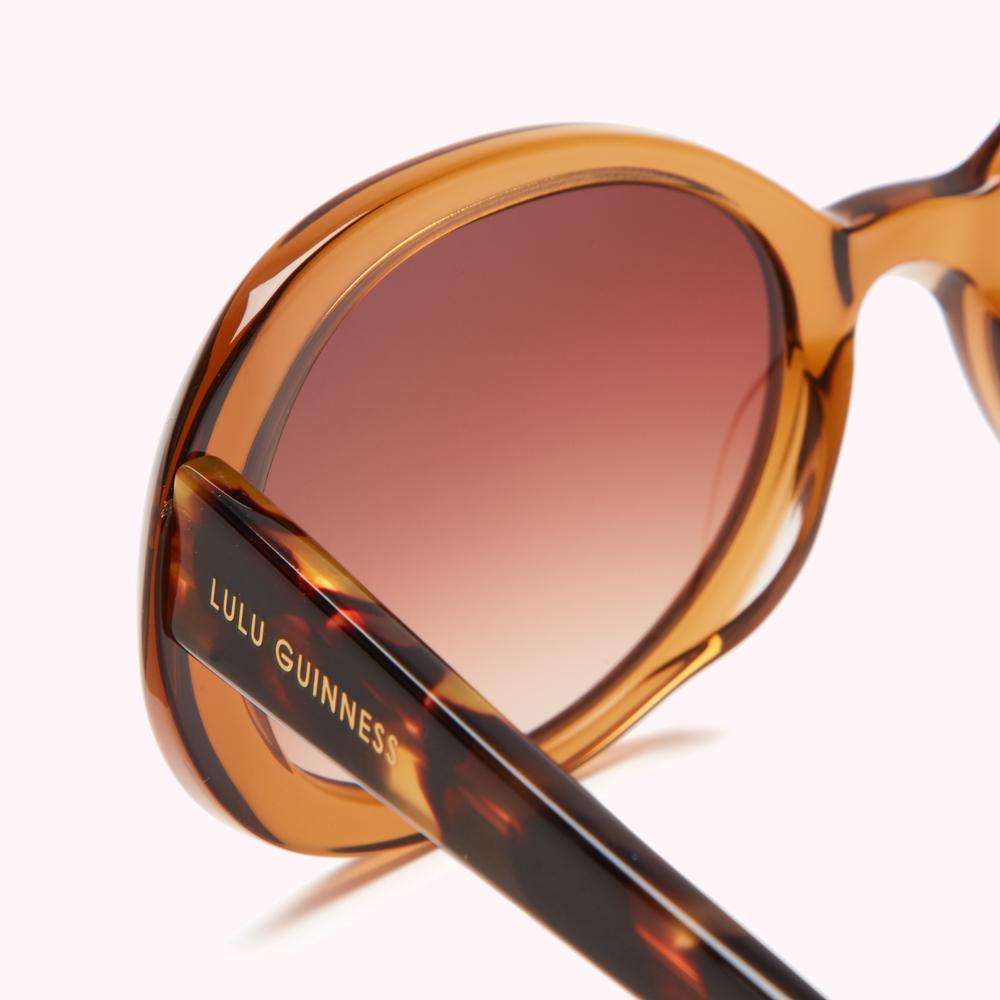 Close-up of brown tortoiseshell Lulu Guinness sunglasses with amber-tinted lenses.
