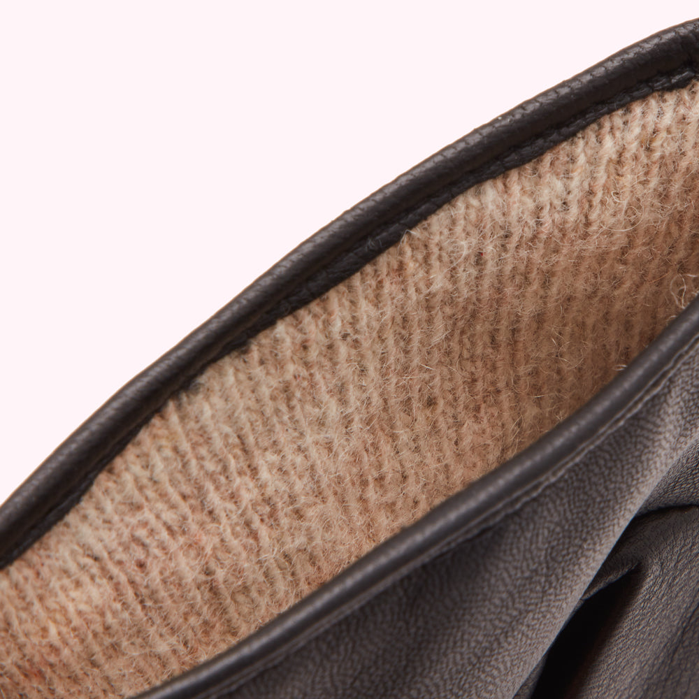 Close-up of the inside of a dark brown leather glove showing a tan, textured lining.