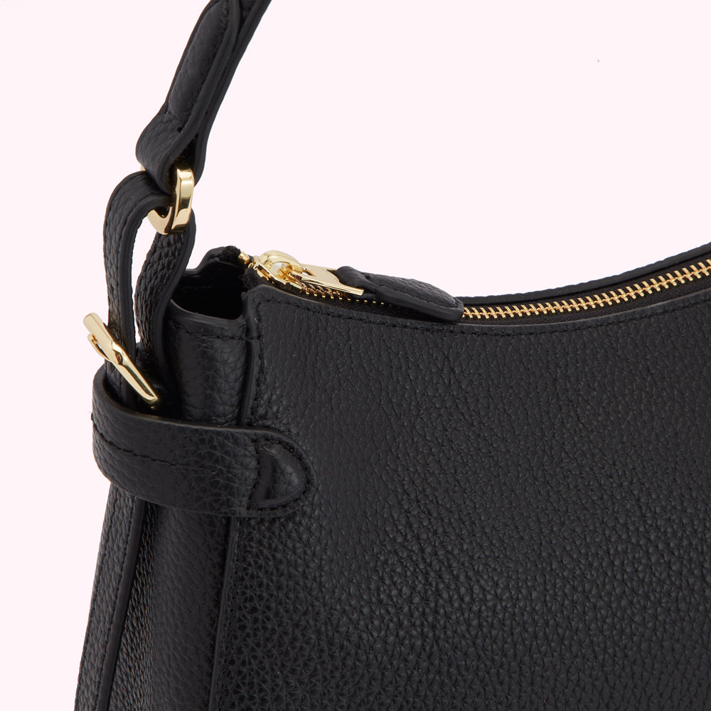 Close-up of a black leather handbag with gold hardware.
