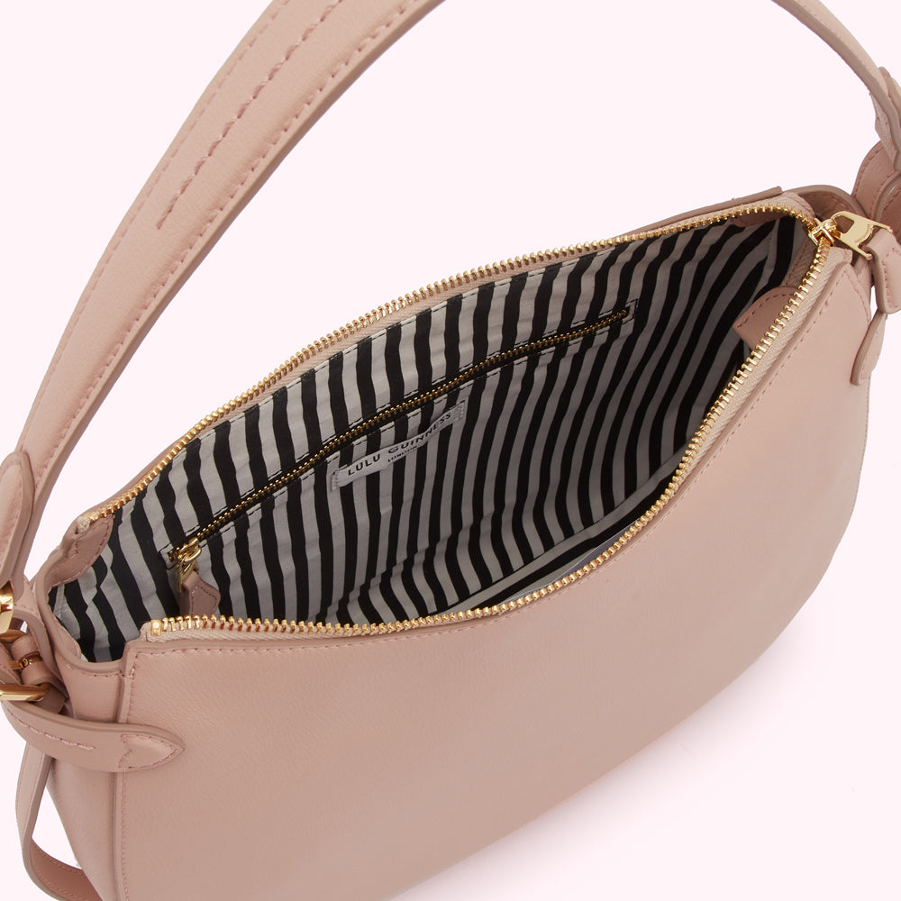 Inside view of a blush-pink Lulu Guinness shoulder bag with a black and white striped interior lining.