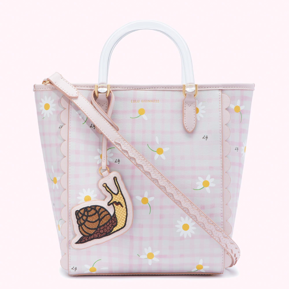 Pink gingham and daisy-print tote bag with clear handles and a snail charm.
