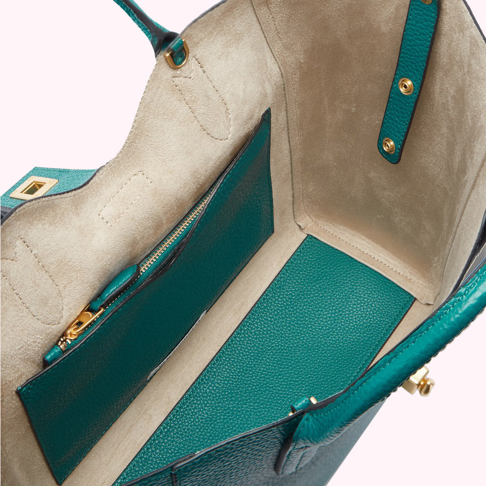 Interior view of a teal leather tote bag with a beige lining and zippered pocket.
